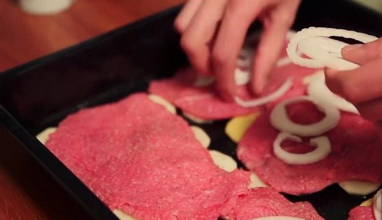 Having pepper and salt the meat, we put onion rings on it.