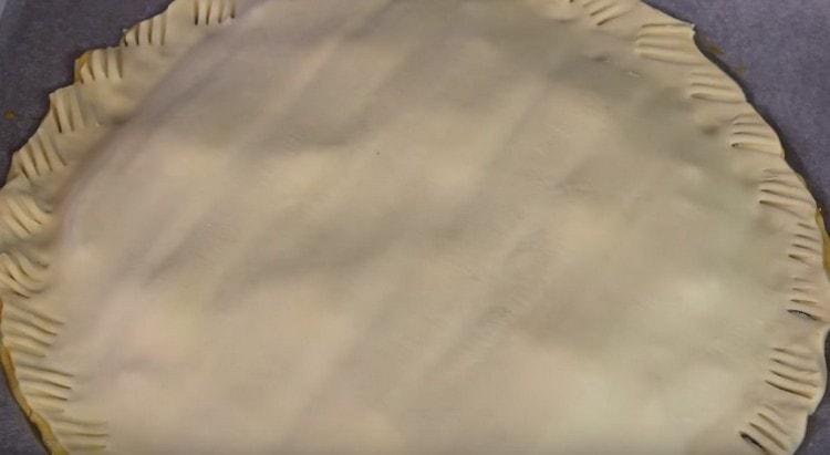 We cover the workpiece with another sheet of dough, press the edges with a fork.