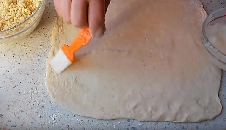 We take out the dough from the refrigerator, roll out and grease with protein.