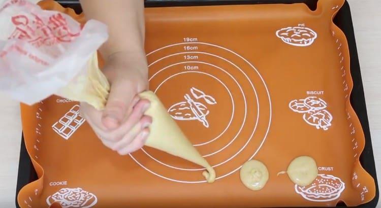 Using a pastry bag, we place cookies on the mat.