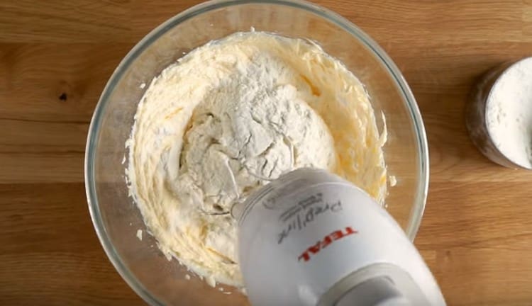 Gradually add flour to the dough, whipping it with a mixer.