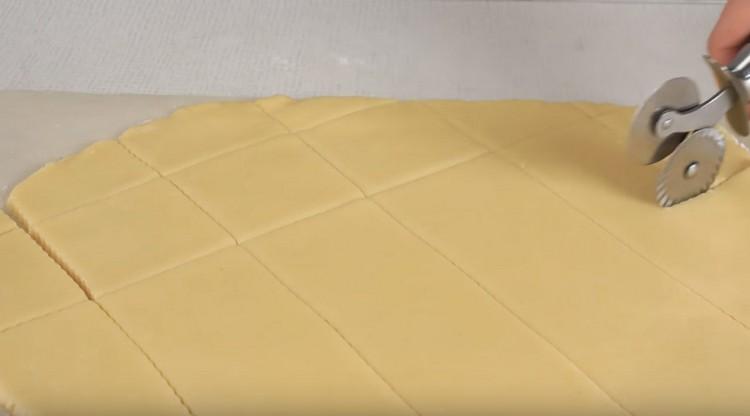 Cut the rolled out dough with a knife for pizza into small squares.