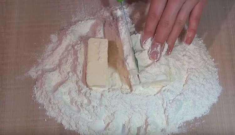 We spread cold butter in flour and chop it into small pieces with a knife.
