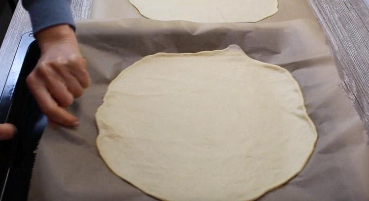 Together with parchment, transfer the dough onto a baking sheet.