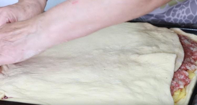 Close the filling with the second half of the dough, rolling it out.