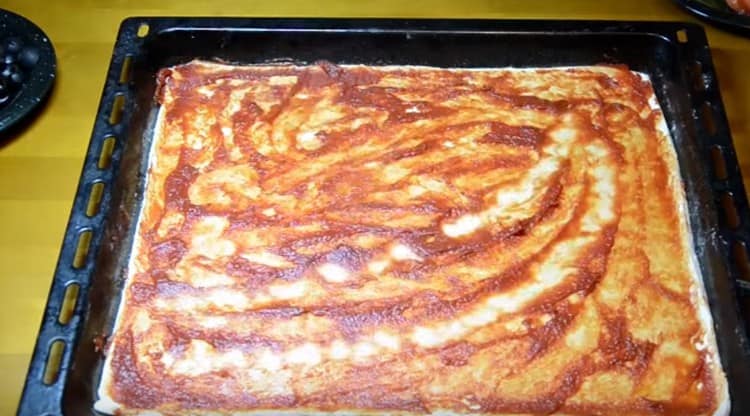 Grease the basis for pizza with tomato sauce.