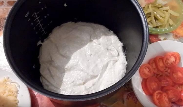 In a greased multicooker bowl, spread the dough.