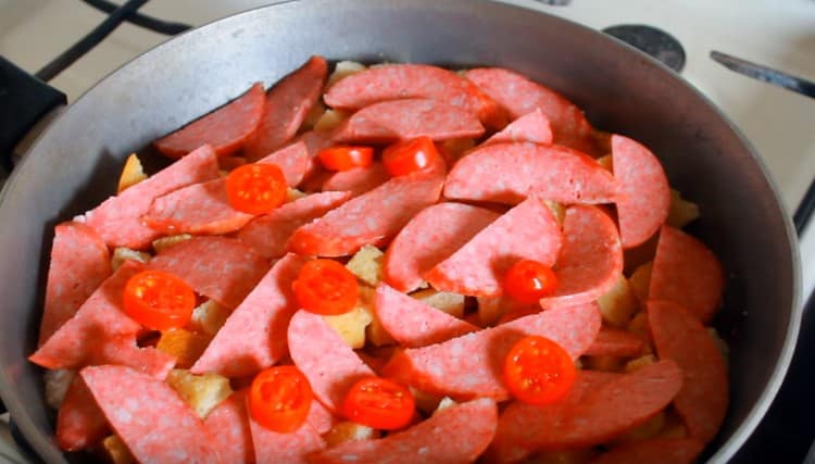 On top of the loaf we lay out slices of sausage and tomatoes.