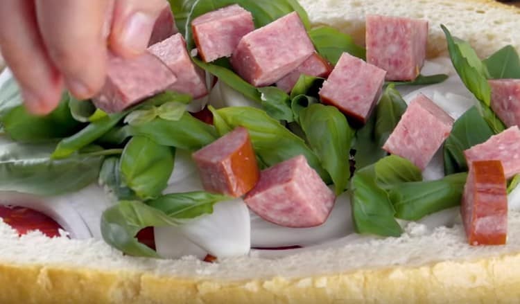 We spread a layer of smoked sausages cut into pieces.