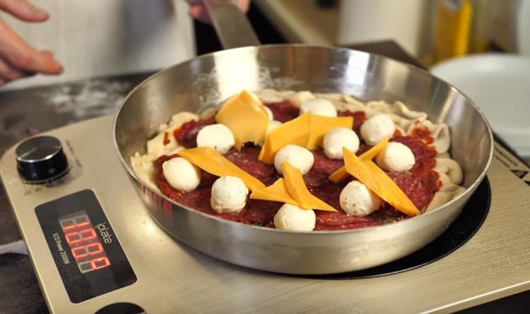Cooking pizza in a pan, covering it with a lid.
