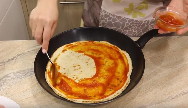 Lubricate the base for pizza with tomato sauce or ketchp.