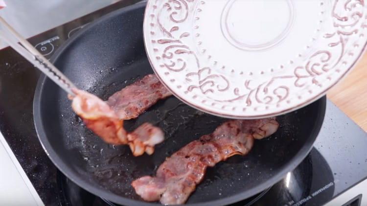 Fry slices of bacon in a pan.