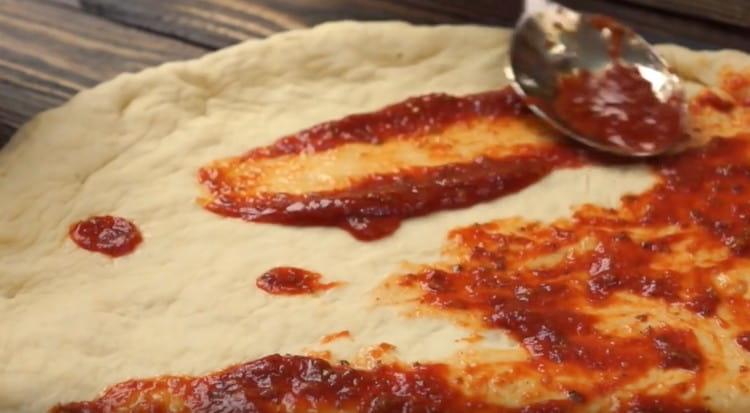 Grease the dough with sauce.