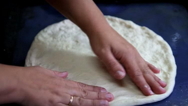 Dividing the dough into 3 parts, each of them is aligned on a greased vegetable oil baking sheet in a circle.