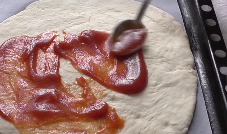 Grease the basis for pizza with tomato sauce.