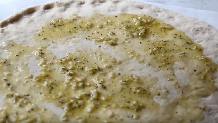 First, grease the pizza base with garlic oil.