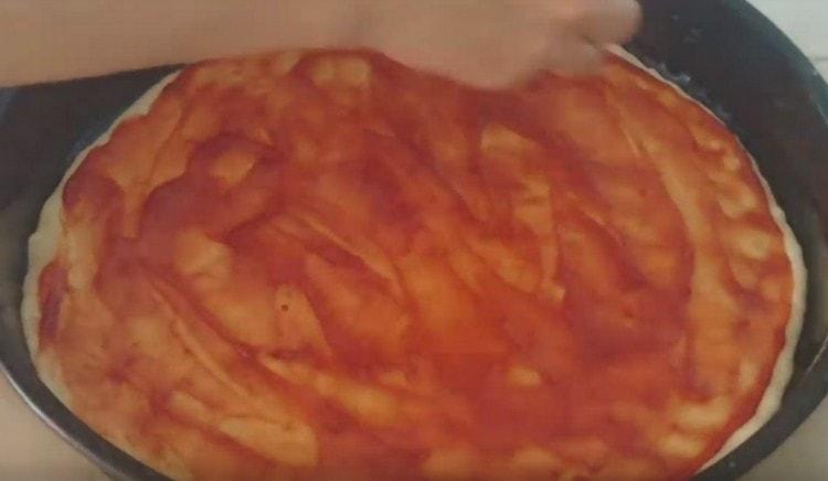 Grease the basis for pizza with ketchup.