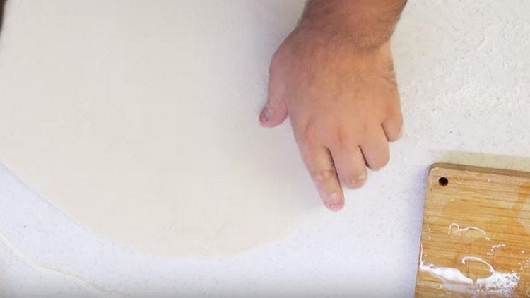 With our hands we stretch the dough on a powdery surface.