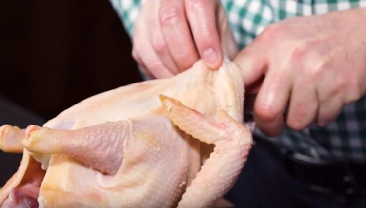 Very carefully separate the skin from the chicken carcass.