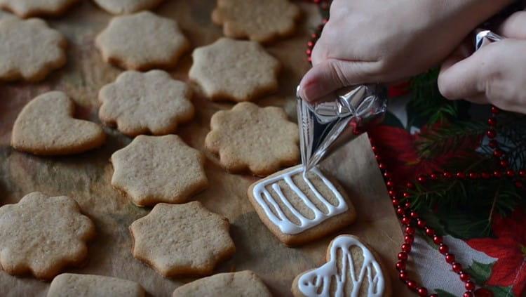 Using a cornet or a pastry bag, decorate cookies with icing.