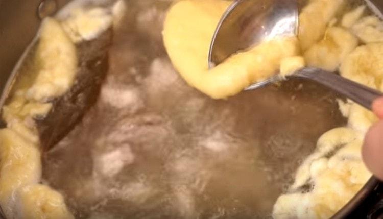 We collect the dough in one spoon, and the other, dipped in water, send it in small portions to the soup.