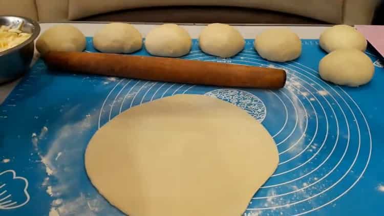 Roll out the dough to make a yeast pie with meat