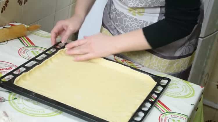 To make a pie with fish and potatoes, put the dough on a baking sheet