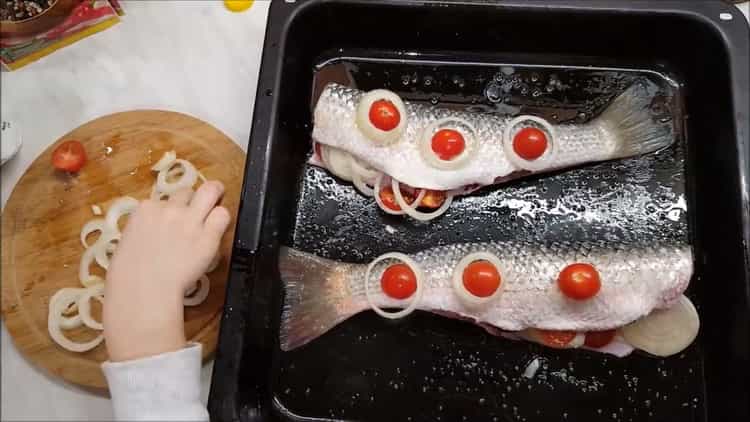 To cook a bearing in the oven, put the tomatoes on the fish