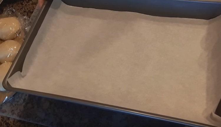 We cover the baking sheet on which we will bake buns with parchment.
