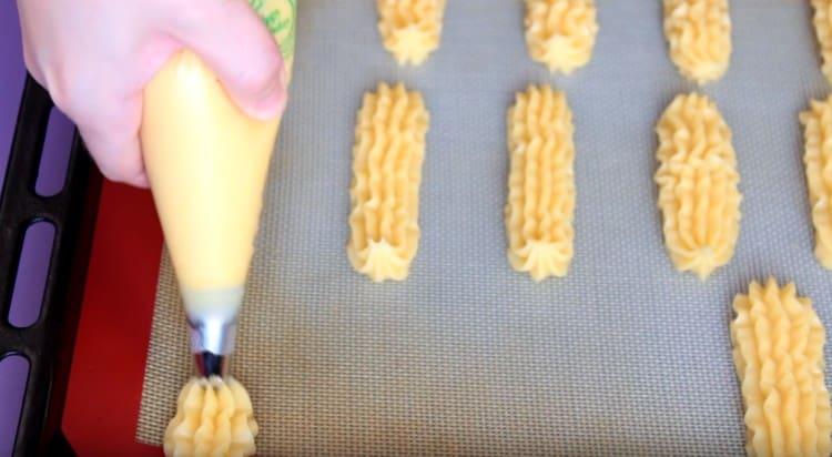 Using a pastry bag, we place the eclairs on a baking sheet.