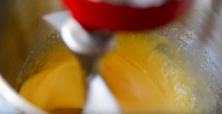 Beat eggs with sugar and vanilla extract using a mixer.