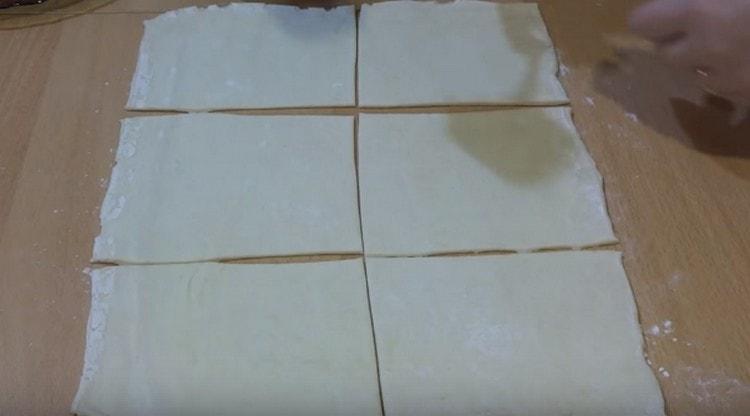 Roll out the puff pastry and cut it into squares.