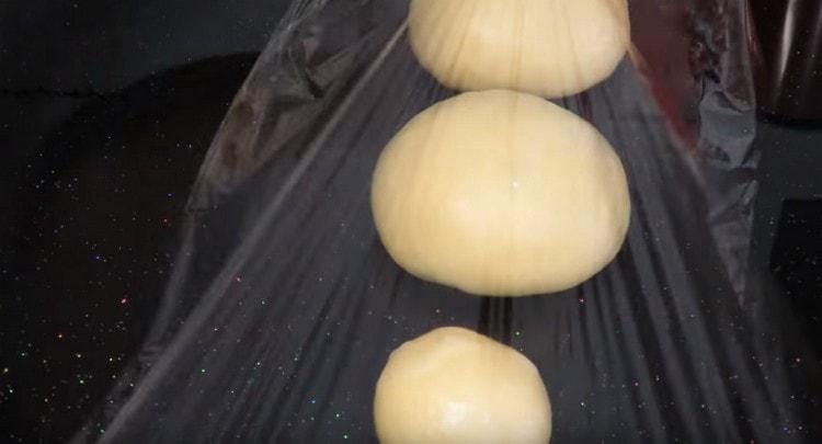 We divide the finished dough into 3 parts, each roll into a ball and cover for about 10 minutes with a film.
