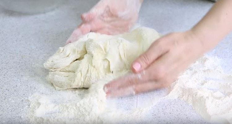 We put the soft dough on the table, roll in flour, knead.