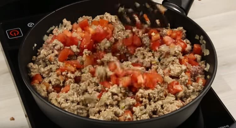 Add tomatoes to the minced meat with onions.