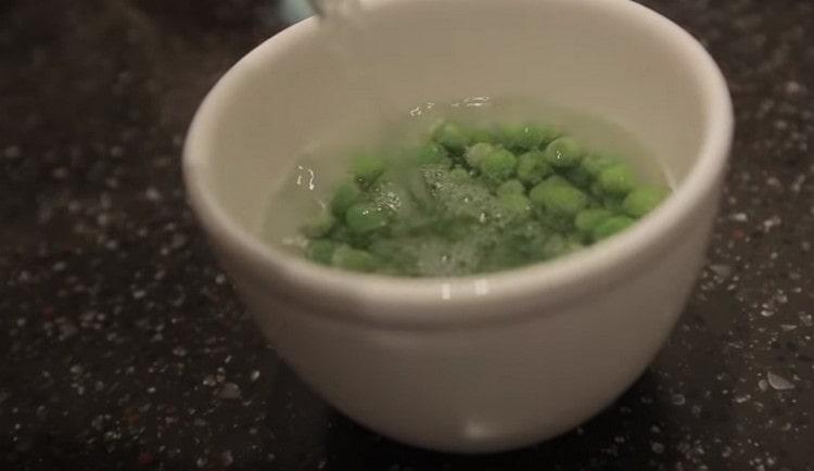 Pour boiled water over frozen green peas.