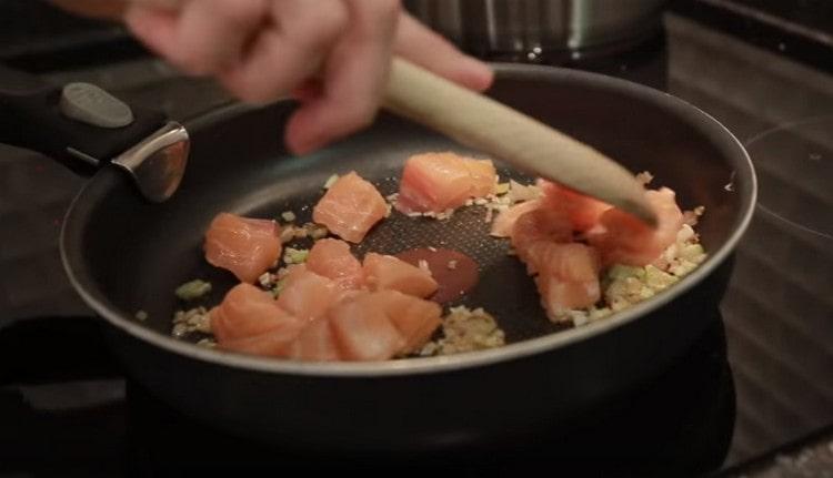 Together with chopped garlic, spread the salmon in a pan to the onion.