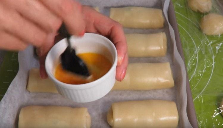 Beat the yolk and grease the pies.