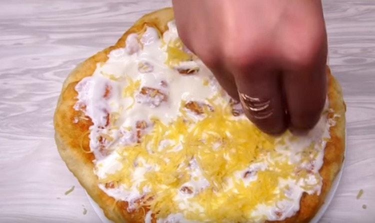 Lubricate ready-made donuts on water with sauce and sprinkle with grated cheese.