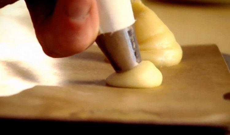 Using a pastry bag, we plant profiteroles on a parchment sheet covered with parchment.