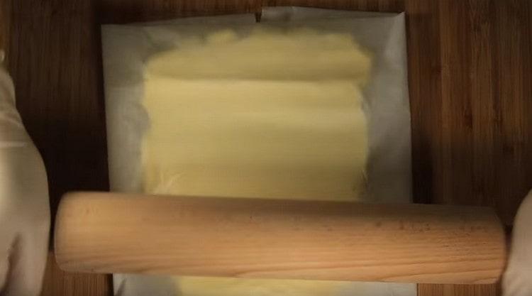 Separately, between two ists of parchment, we roll butter to a square size of 20x20 cm.