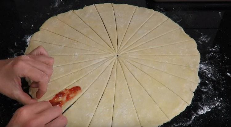 For each triangle of dough we spread a little jam.