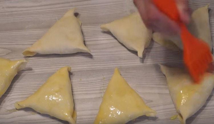 With a mixture of yolk and milk, grease the pies.