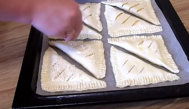 grease the puffs with a beaten egg and sprinkle with sesame seeds.