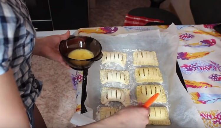 Put the prepared puffs on a baking sheet laid with baking paper and grease with an egg.