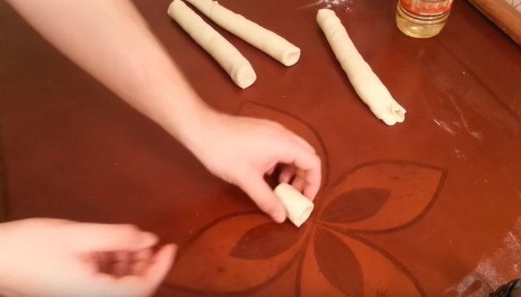 Taking the dough out of the refrigerator, cut the sausages into portioned slices.