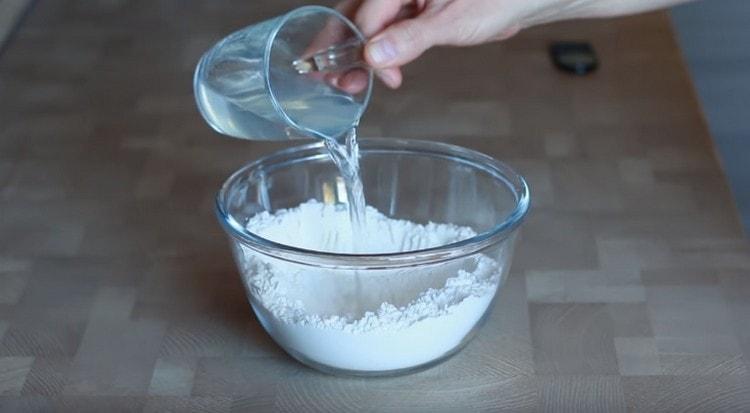 Having made a depression in the flour. pour water there.