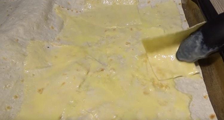 Tear another sheet of pita bread into pieces and, dipping them in a kefir-egg mixture, spread on a large pita bread.