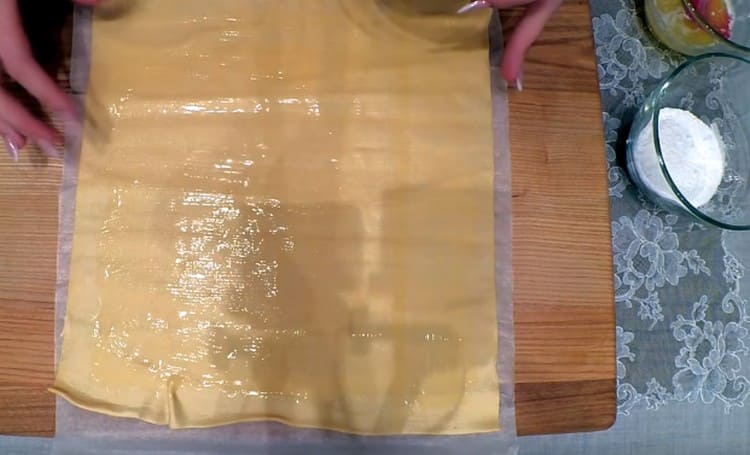 We lay out the puff pastry on a sheet of parchment. grease with melted butter.