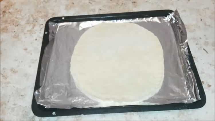 To make pizza with sausage and cheese, roll out the dough